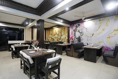 a restaurant with tables and chairs and a painting on the wall at Hotel Areeba by The Golden Taj Group & Hotels in Agra