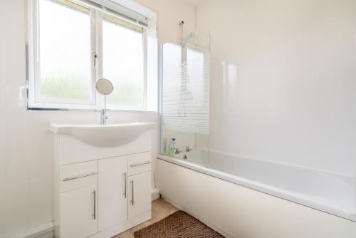 a white bathroom with a sink and a tub and a window at Stylish & Comfortable 3BR Spacious Home with Parking in Greenhill