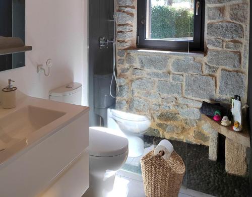 a bathroom with a white toilet and a stone wall at El Chalet de Navacerrada in Navacerrada