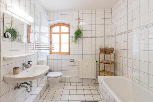 een witte badkamer met een wastafel, een toilet en een bad bij Stadtgut Mölkau Rooms & Apartments in Leipzig