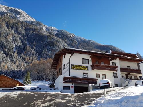 a snow covered building with a mountain in the background at Gästeheim Schmiedhof in Sölden