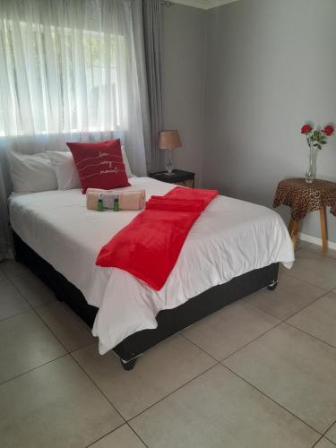 a bedroom with a bed with a red blanket on it at KLOOFIES GUESTHOUSE in Roodepoort