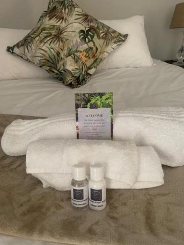a bed with white towels and two bottles of medicine at KLOOFIES GUESTHOUSE in Roodepoort