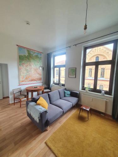 ein Wohnzimmer mit einem blauen Sofa und einem großen Fenster in der Unterkunft Sonniges Altstadt Nest in Magdeburg