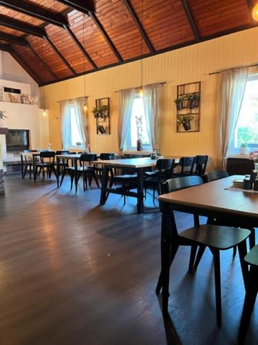 jadalnia ze stołami, krzesłami i oknami w obiekcie Penzion & Restaurace U Vily w mieście Sezimovo Ústí