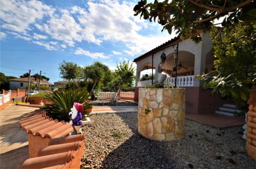 a doll sitting on a bench in front of a house at Villa Olombel in Maçanet de la Selva