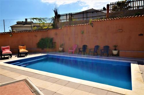 a swimming pool with chairs next to a wall at Villa Olombel in Maçanet de la Selva