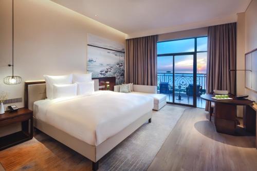 a hotel room with a large bed and a balcony at Pullman Yueyang in Yueyang