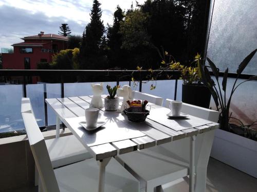 une table blanche et des chaises sur un balcon dans l'établissement Les Delphes, Très beau 2P proche mer et Monaco, à Menton