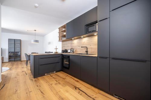 a kitchen with black cabinets and a wooden floor at Apartments Austria in Söll