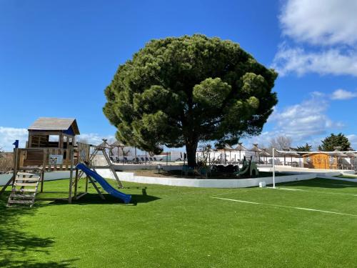 a playground with a tree and a slide at Hotel Mas des Lys in Saintes-Maries-de-la-Mer