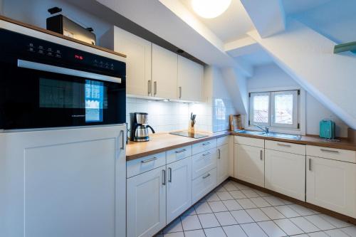 een keuken met witte kasten en een zwart apparaat bij Ferienwohnung 2 - Marktkirchhof in Quedlinburg