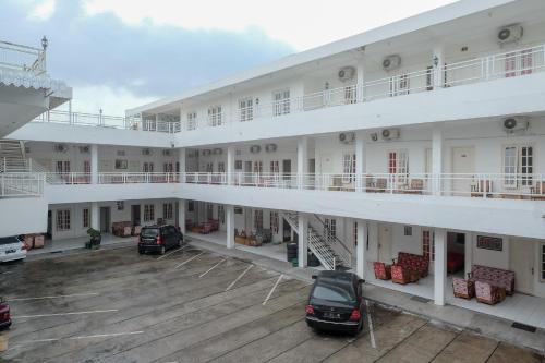 a large white building with cars parked in a parking lot at RedDoorz Plus near UMS Solo in Solo