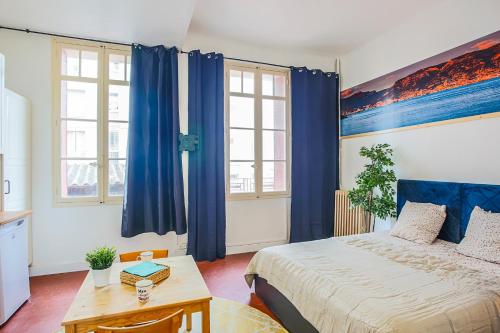 a bedroom with blue curtains and a bed and a table at #1 Toulon CENTRE AU CALME, LUMINEUX, STATIONNEMENT FACILE in Toulon