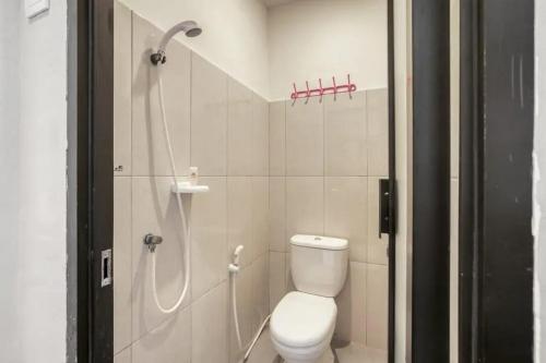 a white bathroom with a shower and a toilet at KoolKost at Bypass Nusa Dua in Nusa Dua