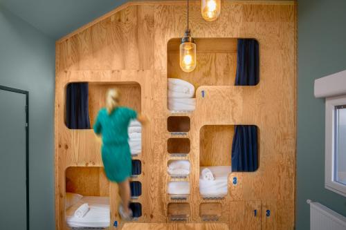 a woman walking through a room with a wall of bunk beds at Eklo Bordeaux Centre Bastide in Bordeaux