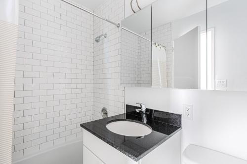 a white bathroom with a sink and a mirror at Murray Hill 1BR w Doorman Gym Pool Parking NYC-583 in New York