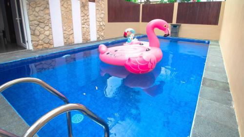 una piscina con un flamenco rosa inflable en el agua en Villa Surga Dunia with Private Pool and Billiard, en Batu
