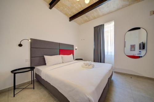 a bedroom with a large white bed and a mirror at Casa Domenico 5 in Valletta