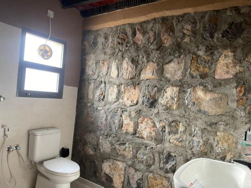 a stone wall in a bathroom with a toilet and a sink at Rose Guesthouse in Al ‘Aqar