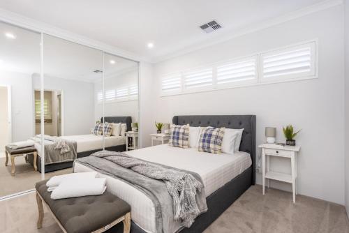 a white bedroom with two beds and a chair at East Vic Park Glamour- EXECUTIVE ESCAPES in Perth