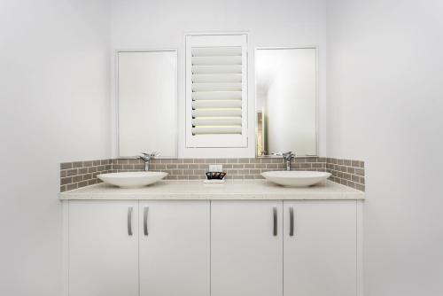 a white bathroom with two sinks and a mirror at East Vic Park Glamour- EXECUTIVE ESCAPES in Perth