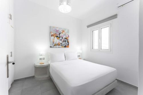 a white bedroom with a white bed and a window at Sunrise Villa Santorini in Vourvoulos