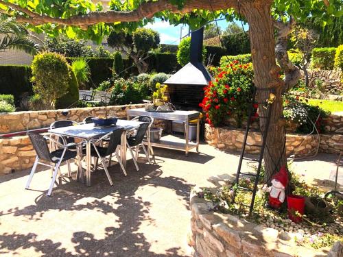 a table and chairs with a grill in a garden at Villa Playa in L'Ametlla de Mar