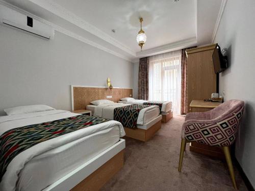 ein Hotelzimmer mit 2 Betten und einem TV in der Unterkunft Hotel Shaherezade Garden in Buxoro