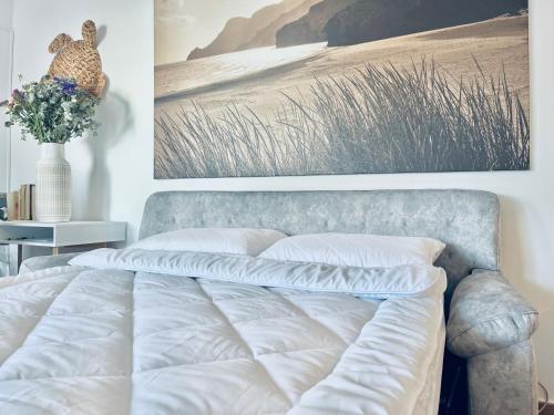 una cama con sábanas blancas y una pintura en la pared en Villa Congrio, en Las Negras