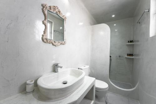 a white bathroom with a sink and a mirror at Sunrise Villa Santorini in Vourvoulos