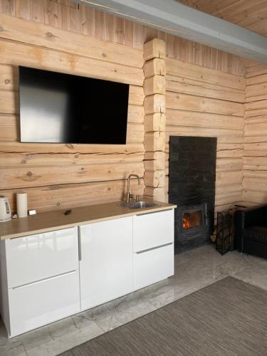 a kitchen with a fireplace and a television on a wall at Dūjas in Duķuri