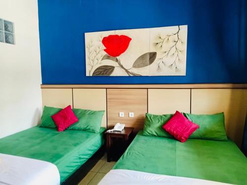 two beds in a room with green and red pillows at Ahlen Pangandaran in Pangandaran