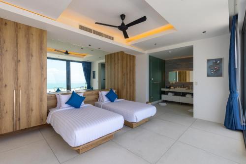 a bedroom with two beds and a ceiling fan at Villa Blue View Luxe in Mae Nam