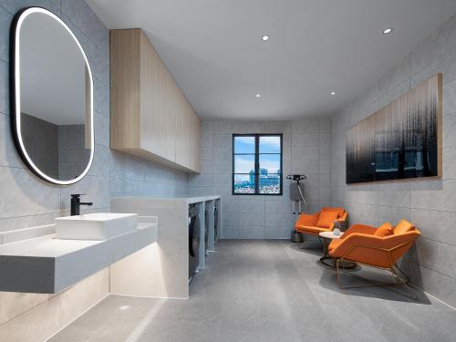 La salle de bains est pourvue d'une chaise orange et d'un lavabo. dans l'établissement Country Inn & Suites by Radisson - Taishan East Branch, à Taishan