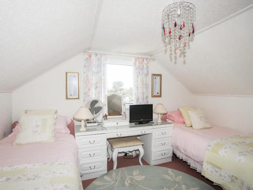 - une chambre avec 2 lits et un bureau avec une télévision dans l'établissement Berllys, à Criccieth