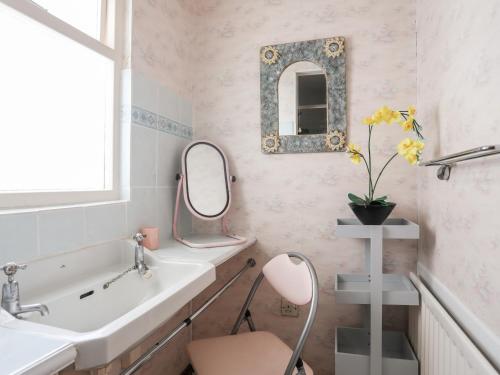 La salle de bains est pourvue d'un lavabo, d'un miroir et d'une chaise. dans l'établissement Berllys, à Criccieth