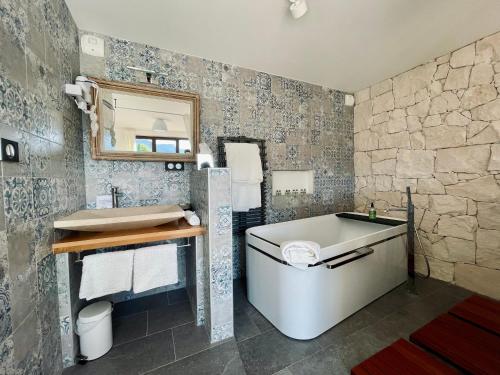 baño con bañera y pared de piedra en Escondida, en Niza