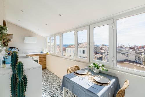 - une cuisine et une salle à manger avec une table et des fenêtres dans l'établissement Casa Belvedere - duplex atypique avec vue féerique & parking souterrain, à La Ciotat