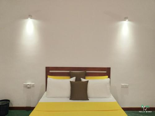 a bedroom with a bed with two lights on the wall at Yala wind in Tissamaharama