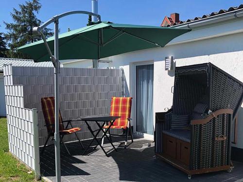 Bungalow Rudensicht في Freest: فناء مع طاولة ومظلة خضراء