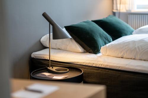 a bed with green pillows and a lamp on a table at Skanderborg Park in Skanderborg