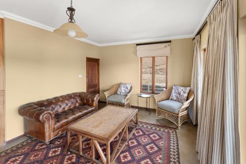 a living room with a leather couch and two chairs at Lake House @ Misty Ridge in Himeville