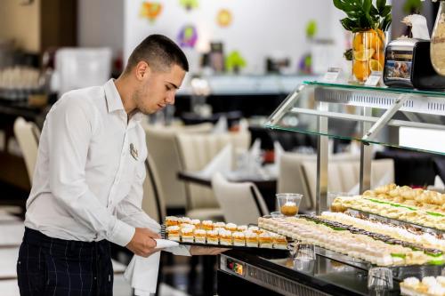 a man holding a tray of food in a restaurant at Prestige Deluxe Hotel Aquapark Club - All inclusive in Golden Sands
