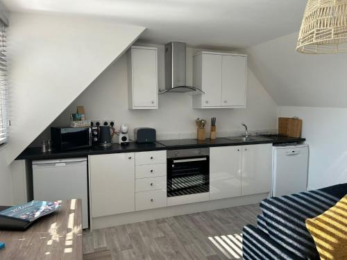 a kitchen with white cabinets and a black counter top at Weymouth Harbour Luxury Apartment in Weymouth