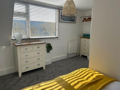 a bedroom with a bed and a dresser and a window at Weymouth Harbour Luxury Apartment in Weymouth