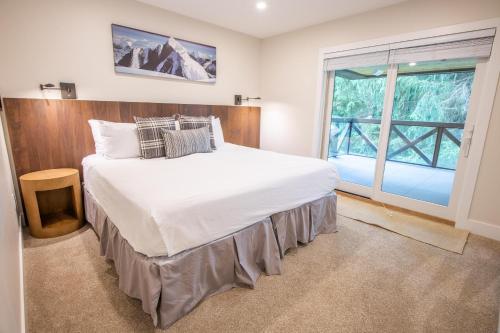 ein Schlafzimmer mit einem großen weißen Bett und einem Fenster in der Unterkunft Pinnacle Ridge 23 - Ski In Ski Out, Newly Renovated, Private Hot Tub, Gas Fireplace in Whistler