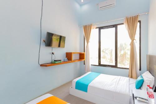 a bedroom with a bed and a tv on a wall at Sans Borobudur Homestay Banyuwangi in Banyuwangi