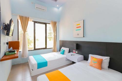 a bedroom with two beds and a window at Sans Hotel Borobudur Banyuwangi in Banyuwangi