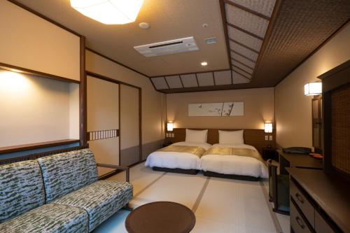 a hotel room with two beds and a couch at Jozankei Onsen Yurakusoan in Jozankei